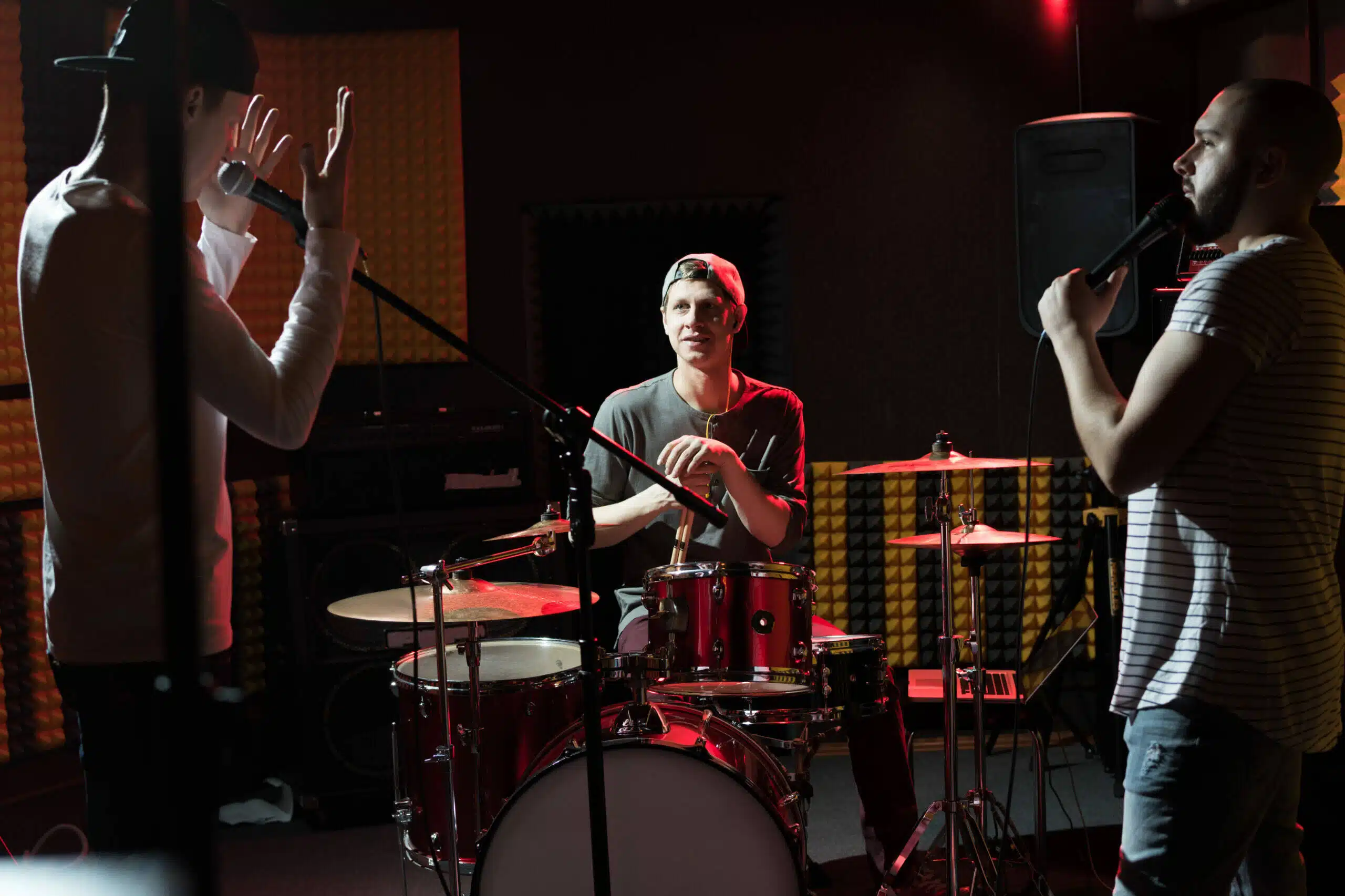 Portrait of modern hip-hop band rehearsing in recording studio lit by dim lights while making new album